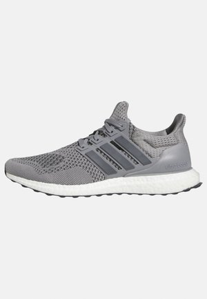 Scarpa sportiva grigia con tomaia in rete traspirante, dettagli a tre strisce e una suola intermedia Boost bianca per un'ammortizzazione ottimale.
