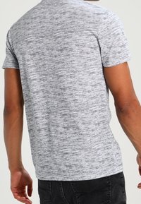 T-shirt gris à manches courtes avec une texture marbrée, doté d'un col rond. Le design du dos est simple, sans détails ni motifs supplémentaires.