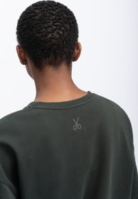 Donkergroen sweatshirt met een ronde halslijn, voorzien van een subtiele schaarafbeelding op de bovenrug, gemaakt van zacht katoen.