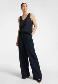 Canotta di raso blu marina con una vestibilità ampia, abbinata a pantaloni a gamba larga a vita alta in blu marina abbinato, caratterizzati da linee pulite e senza hardware visibile.