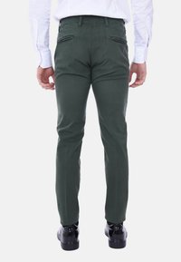 Chinos verdi in cotone con vestibilità slim. Presentano tasche posteriori e orli; indossati con scarpe nere. Design semplice e funzionale.