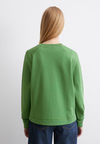 Grön sweatshirt med rund hals och ribbade muddar, tillverkad i mjukt material. Har raglanärmar och en enkel design.