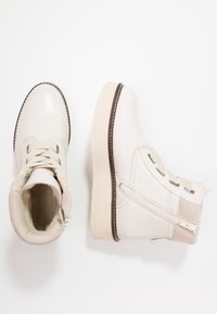 Białe skórzane botki za kostkę z teksturowanymi kremowymi podeszwami, okrągłym noskiem, sznurowanym przodem, bocznym zamkiem błyskawicznym i zamszowymi akcentami. Widoczne przeszycia.