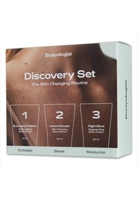 Entdeckungsset mit drei Körperpflegeprodukten in schlanker Verpackung; die Farben sind neutral mit weißem Text und einem strukturierten Hintergrund.