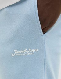 Jogging en coton bleu clair avec une texture lisse, orné du logo brodé blanc "Jack & Jones Essentials Dept." sur la zone de la poche gauche.