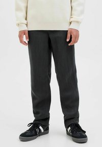 Dark gray trousers with a smooth texture, straight-cut design, and a subtle sheen, paired with black sneakers featuring white accents.