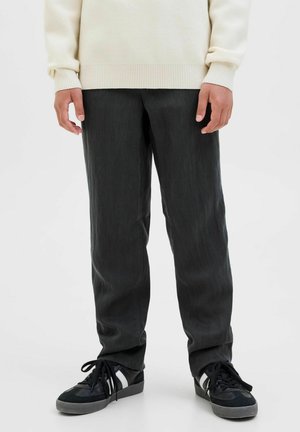 Dunkelgraue Hose mit glattem Textur, geradem Schnitt und subtiler Feinheit, kombiniert mit schwarzen Sneakern mit weißen Akzenten.