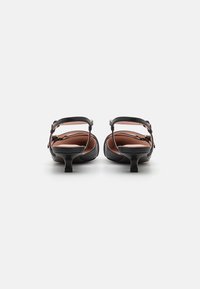 Sorte hælede sandaler med stropdesign, åben ryg og lille hæl. Glat lædermateriale med en kontrasterende lys indvendig. Justerbar spænde.