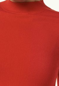 Primer plano de un suéter rojo de punto acanalado con un cuello redondo alto en una persona.