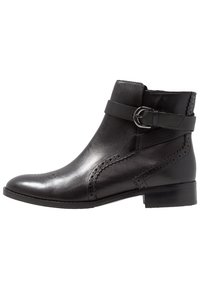 Svart läderankelboots med slät yta, dekorativa brogue-detaljer, sidobuckelrem och en modest blockklack.
