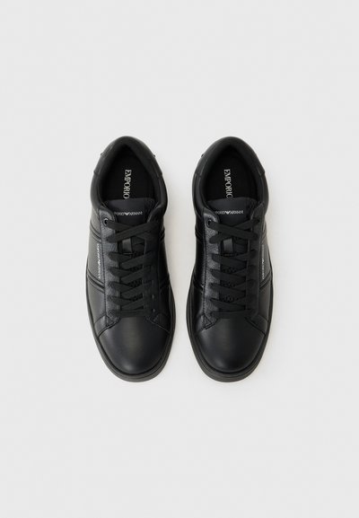 Zapatillas de cuero negras con una textura suave, con un diseño clásico, puntera redonda y cordones. Detalle de franjas en el costado notable.
