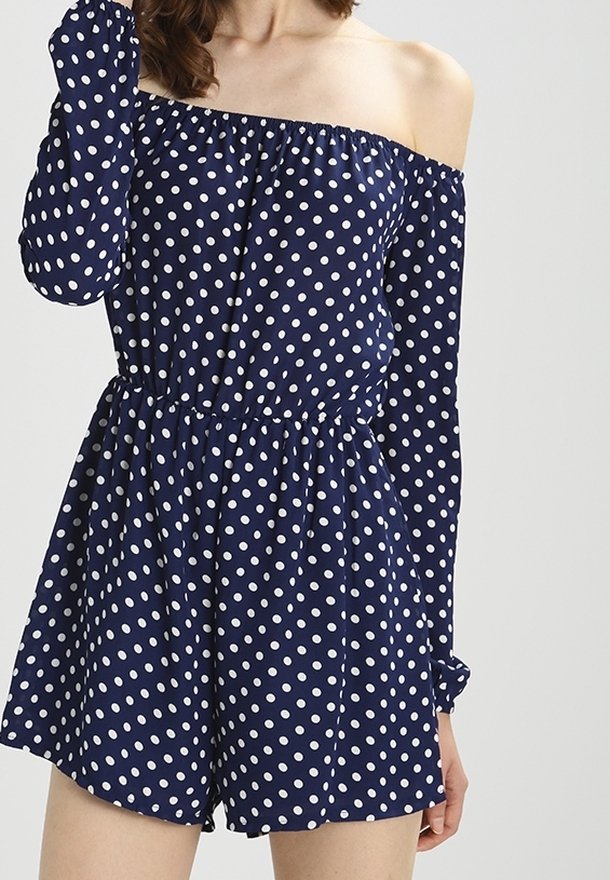 Robe courte marine à épaules dénudées avec des pois blancs, manches longues, taille élastique et poignets froncés. Tissu doux avec une coupe décontractée.