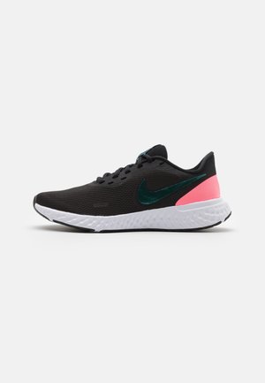 Chaussure de course Nike noire avec logo swoosh vert foncé, accent rose au talon, semelle texturée blanche et lacets noirs sur un fond neutre.