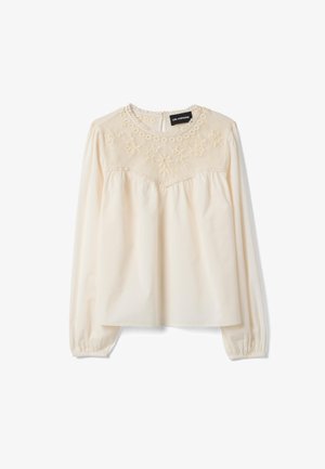 Blusa de manga larga color crema con yugo de encaje bordado y escote redondo, tela fruncida debajo del yugo y puños elásticos.
