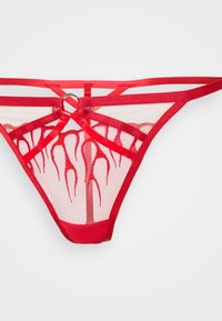 Tanga de malha vermelha com detalhes de tiras verticais, apresentando um padrão de chamas em uma cor contrastante e um detalhe em anel metálico na parte de trás.