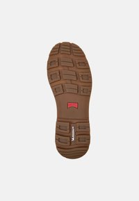 Suola di scarpa in gomma marrone con un motivo di battistrada testurizzato, caratterizzata da sezioni rialzate e un logo rosso. Accenti incisi "CAMper" e "MICHELIN".