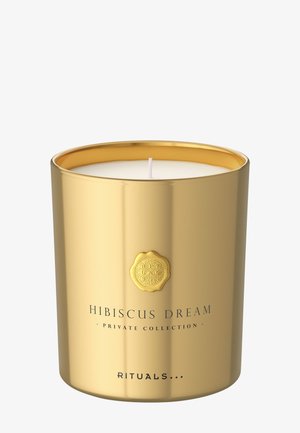 Guldfarvet metal lysestage med en hvid voks inderside. Har teksten "Hibiscus Dream" og et dekorativt præget logo på forsiden.