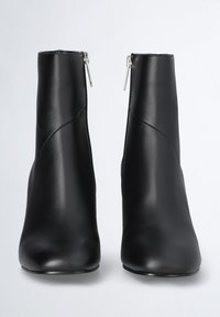 Czarne skórzane botki za kostkę o gładkiej teksturze, z bocznym zamkiem i szpiczastym noskiem, zaprojektowane w eleganckim, minimalistycznym stylu.