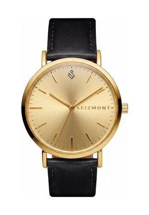 Guld Seizmont armbåndsur med sort læderrem, minimalistisk urskive, gyldne timeindikatorer og tre gyldne visere, der viser 10:10:37.