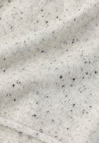 Lichtgrijze gebreide stof met een gespikkeld patroon van zwarte en subtiele rode vlekken, met een zachte textuur en een gladde afwerking.