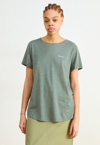 Zelené tričko s krátkym rukávom a okrúhlym výstrihom, vyrobené z mäkkej látky, s malým bielym logom "ROXY" na ľavej strane hrude.