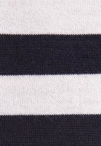 Gros plan sur un tissu tricoté avec des rayures horizontales noires et blanches montrant la texture et les détails des mailles.