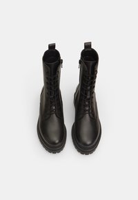Bottes noires en cuir à la cheville avec lacets sur le devant et fermetures éclair latérales, présentant une texture lisse et des semelles en caoutchouc robustes pour une meilleure adhérence.