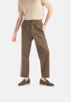 Pantalon marron taille haute, coupe droite, en mélange de coton, avec passants de ceinture, poches avant, associé à des mocassins en daim marron.
