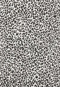 Tissu à imprimé léopard noir et blanc présentant une surface texturée avec un motif plissé. Les motifs varient en taille et en disposition.