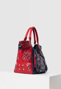 Czerwona i granatowa torebka wykonana ze skóry, ozdobiona wzorami w paisley, z podwójnymi uchwytami i suwakowymi akcentami. Teksturowana powierzchnia z dekoracyjnym przeszyciem.