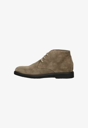 Bottine en suède brun clair avec semelle noire et deux lacets beiges, vue de côté, design minimaliste, logo NG près du col de la cheville.