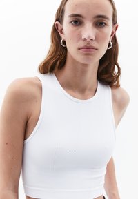 Top corto blanco con textura acanalada y escote redondo, diseñado con costuras de estilo atlético para un ajuste ceñido.