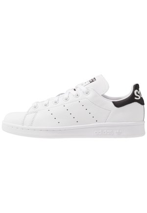 White leather sneaker with a low profile, perforated side detail, textile heel tab in black, and rubber sole. Features lace-up closure.