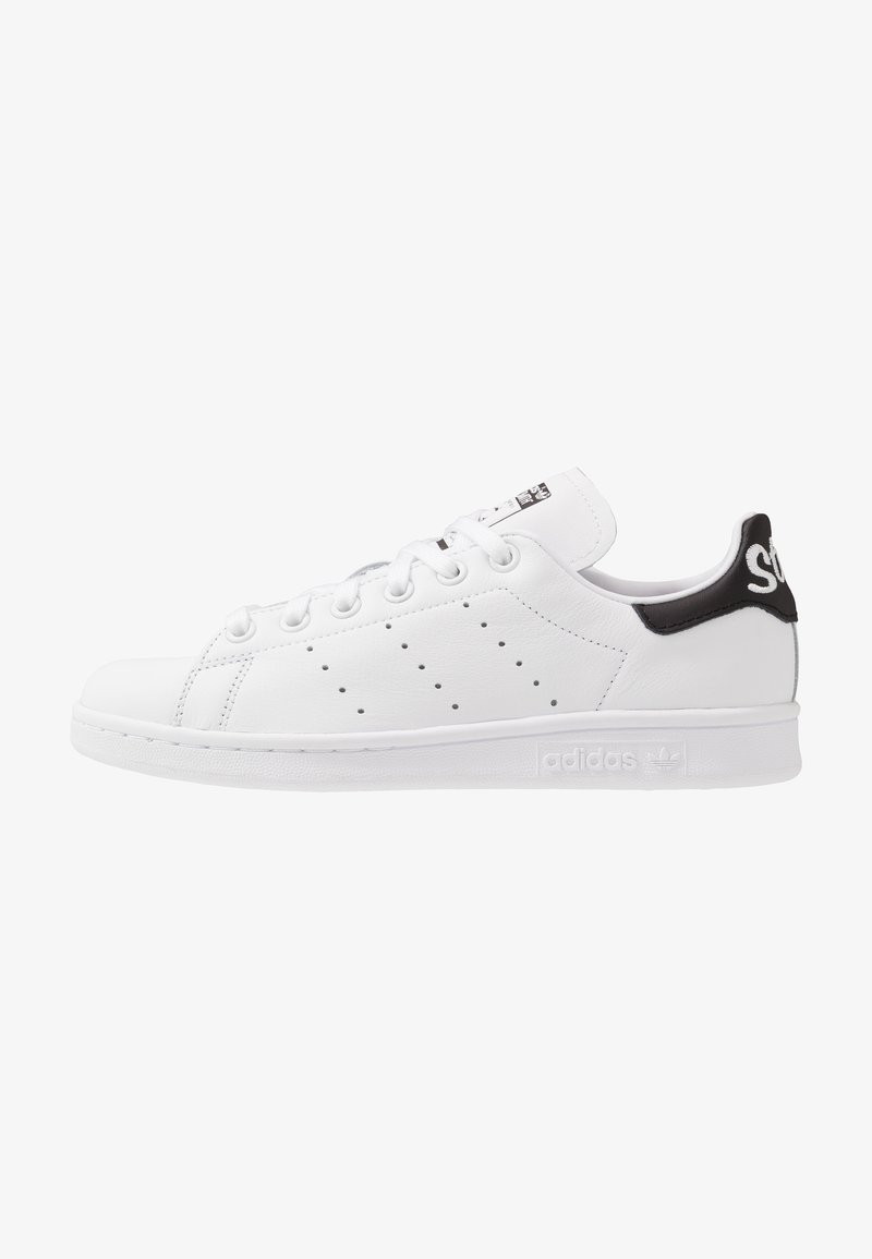 White leather sneaker with a low profile, perforated side detail, textile heel tab in black, and rubber sole. Features lace-up closure.