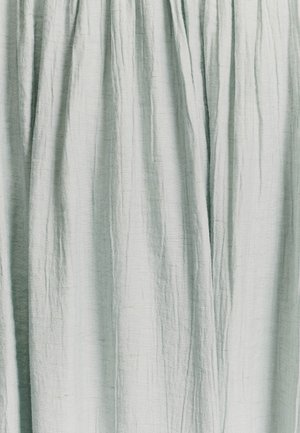 Tissu texturé bleu clair avec des plis drapés, affichant une surface douce, légèrement irrégulière et un subtil éclat.