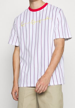 Witte T-shirt met korte mouwen met verticale rode strepen, een rode geribbelde kraag en gouden cursieve tekst op de voorkant. Zacht katoenen materiaal.