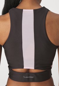 Urheilullinen musta crop-top, jossa on vaaleanpunainen verkkopaneeli keskellä, pyöreä pääntie ja tiukka fit, suunniteltu aktiiviseen pukeutumiseen.