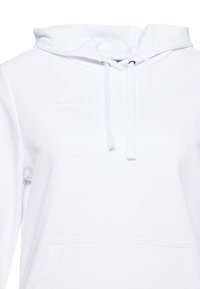 Witte hoodie gemaakt van zachte stof, met een voorzak en koordjes, en een subtiele logo op de borst.