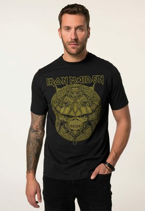 Zwarte katoenen t-shirt met een gouden grafisch ontwerp van het gezicht van een krijger met hoorns, gedetailleerde patronen, en de tekst "IRON MAIDEN" erboven.