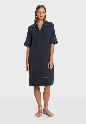 Robe bleu marine avec col, manches courtes et surpiqûres blanches contrastantes. Elle arrive juste au-dessus du genou, confectionnée dans un tissu lisse.