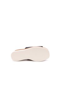 Scarpa slip-on nera con tomaia liscia e un accento marrone. Presenta una suola bianca testurizzata e un design a punta rotonda.