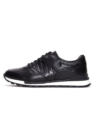 Zapatillas deportivas negras con un diseño de paneles de cuero liso y texturizado. Incluyen cierre con cordones, entresuela blanca y suela de goma negra.