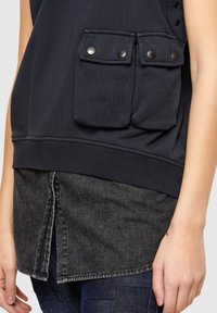 Black sweatshirt with dual buttoned chest pockets and ribbed hem, layered over a dark gray denim shirt featuring a split back.