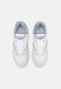 Chaussures de sport blanches et beige avec une tige en cuir texturé, des accents en mesh, un bout arrondi, des lacets plats et un logo sur la languette.