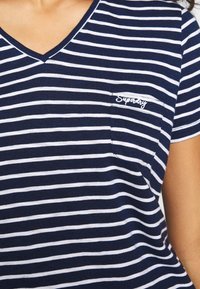 Granatowo-biały t-shirt w paski, z krótkim rękawem i dekoltem w serek, posiadający małą kieszonkę na piersi oraz haftowane logo "Superdry".