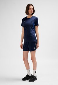 Marineblaues Sportoutfit bestehend aus einem kurzärmligen Oberteil und Shorts, gefertigt aus feuchtigkeitsableitendem Stoff. Mit einem Logo und seitlichen Details versehen.