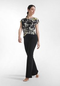 Czarna i biała bluzka w kwiaty z krótkim rękawem i żółtymi akcentami, zestawiona z czarnymi rozszerzanymi spodniami. Miękka tkanina, gładka faktura i dopasowany krój.