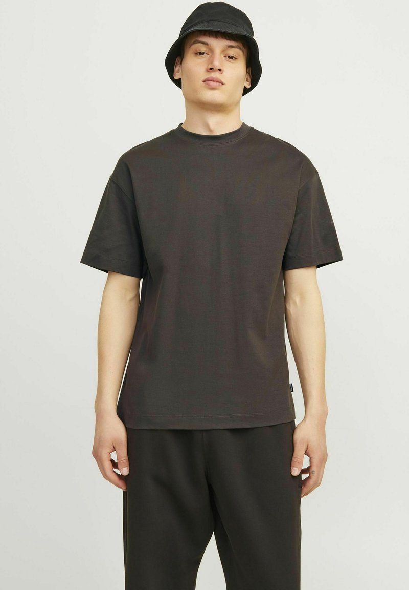 T-shirt in cotone grigio scuro con vestibilità rilassata, maniche corte e collo a giro, abbinato a pantaloni scuri coordinati. Design semplice, senza motivi.