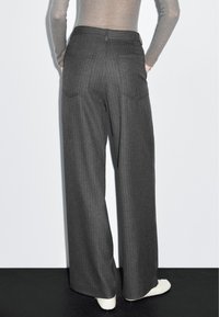 Wijde broek in donkergrijze stof met een streepmotief. Bevat twee achterzakken en een hoge taille met een gladde afwerking.