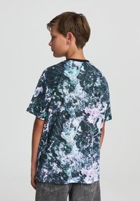 Koszulka z krótkim rękawem w wielokolorowy abstrakcyjny wzór na ciemnym tle z jasnymi akcentami, z okrągłym dekoltem i luźnym krojem.